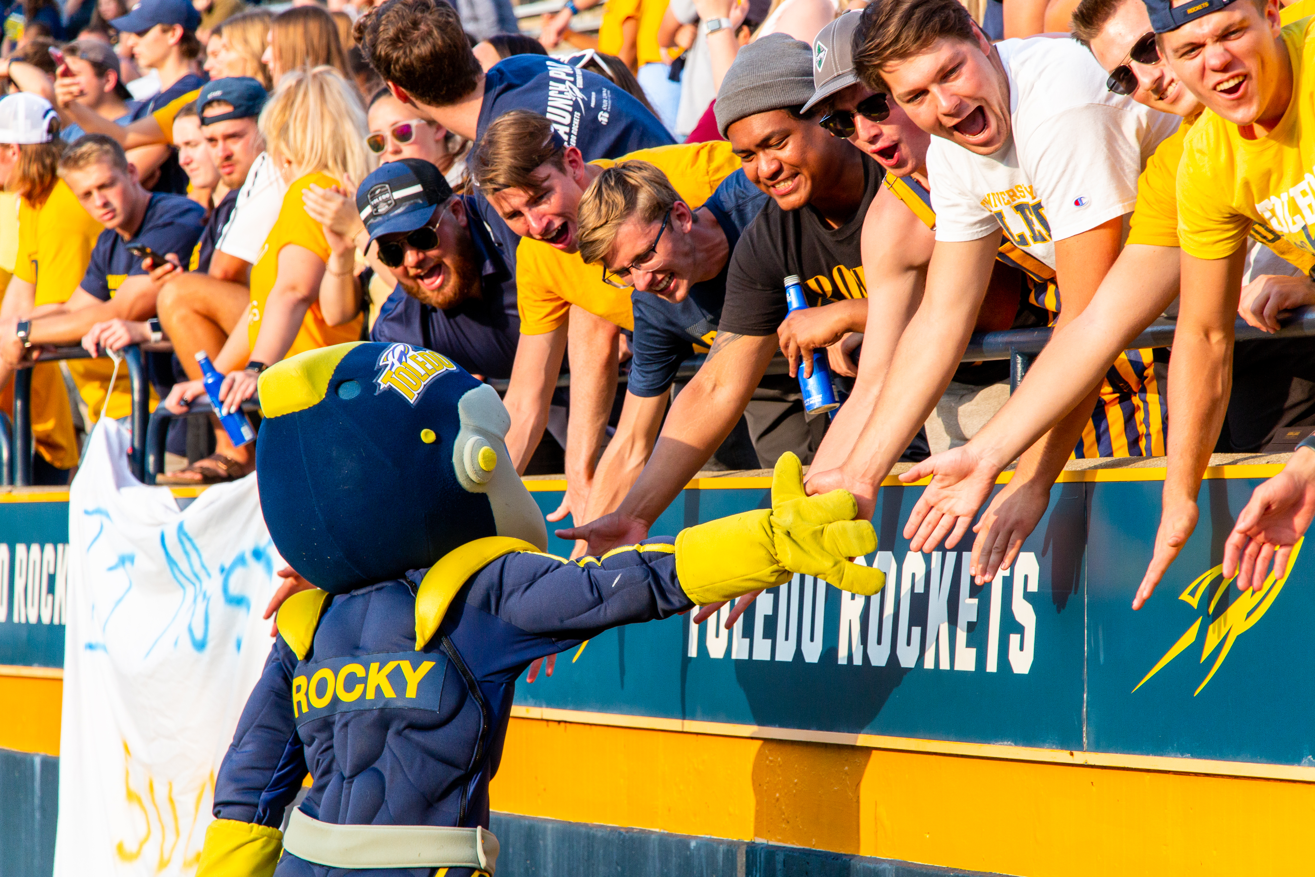 Toledo mascot Rocky is giving a group of fans a high five in the Glass Bowl.