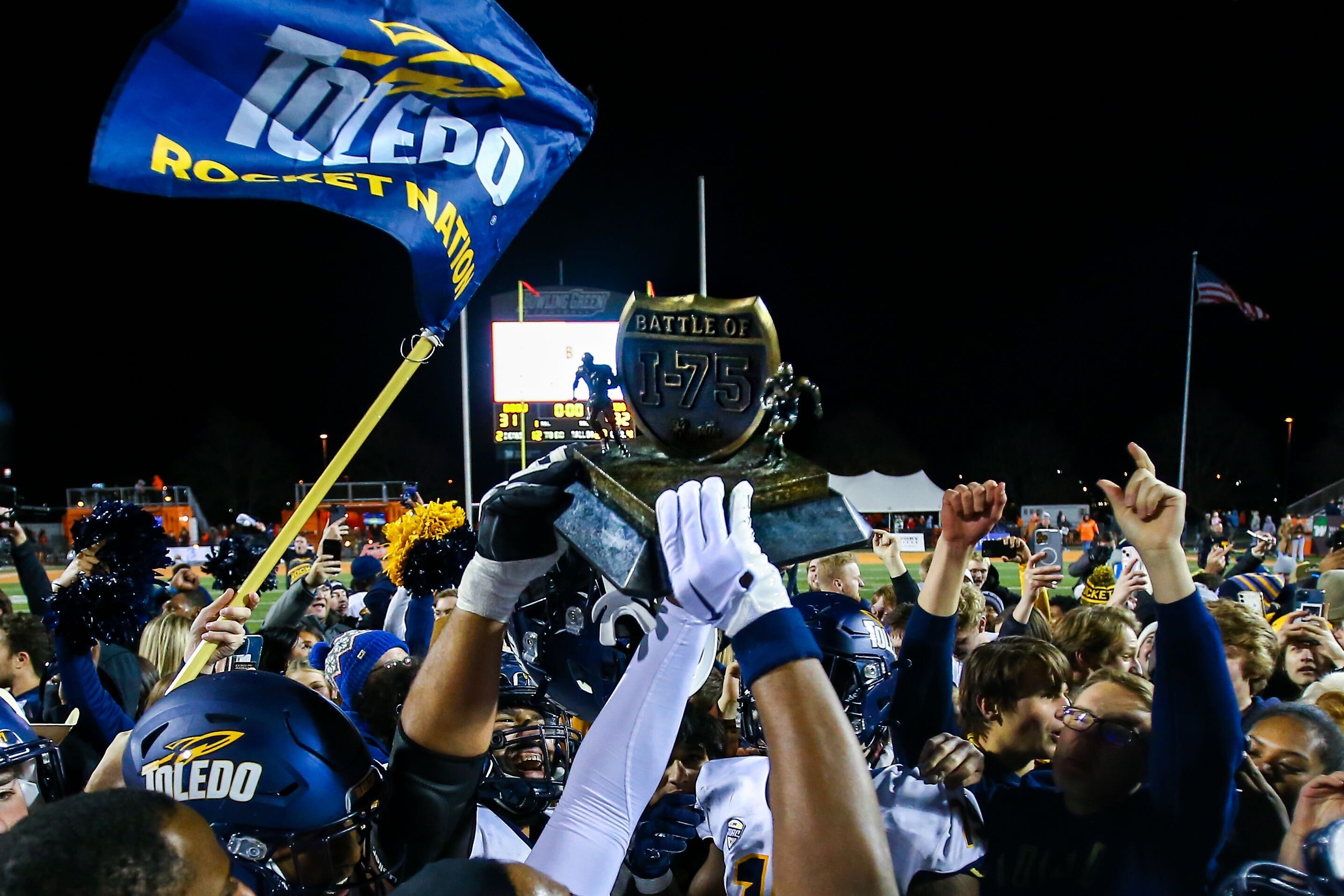 A photo of hands holding the Football Battle of I-75 trophy in the air in celebration after the football team beat Bowling Green in 2023.