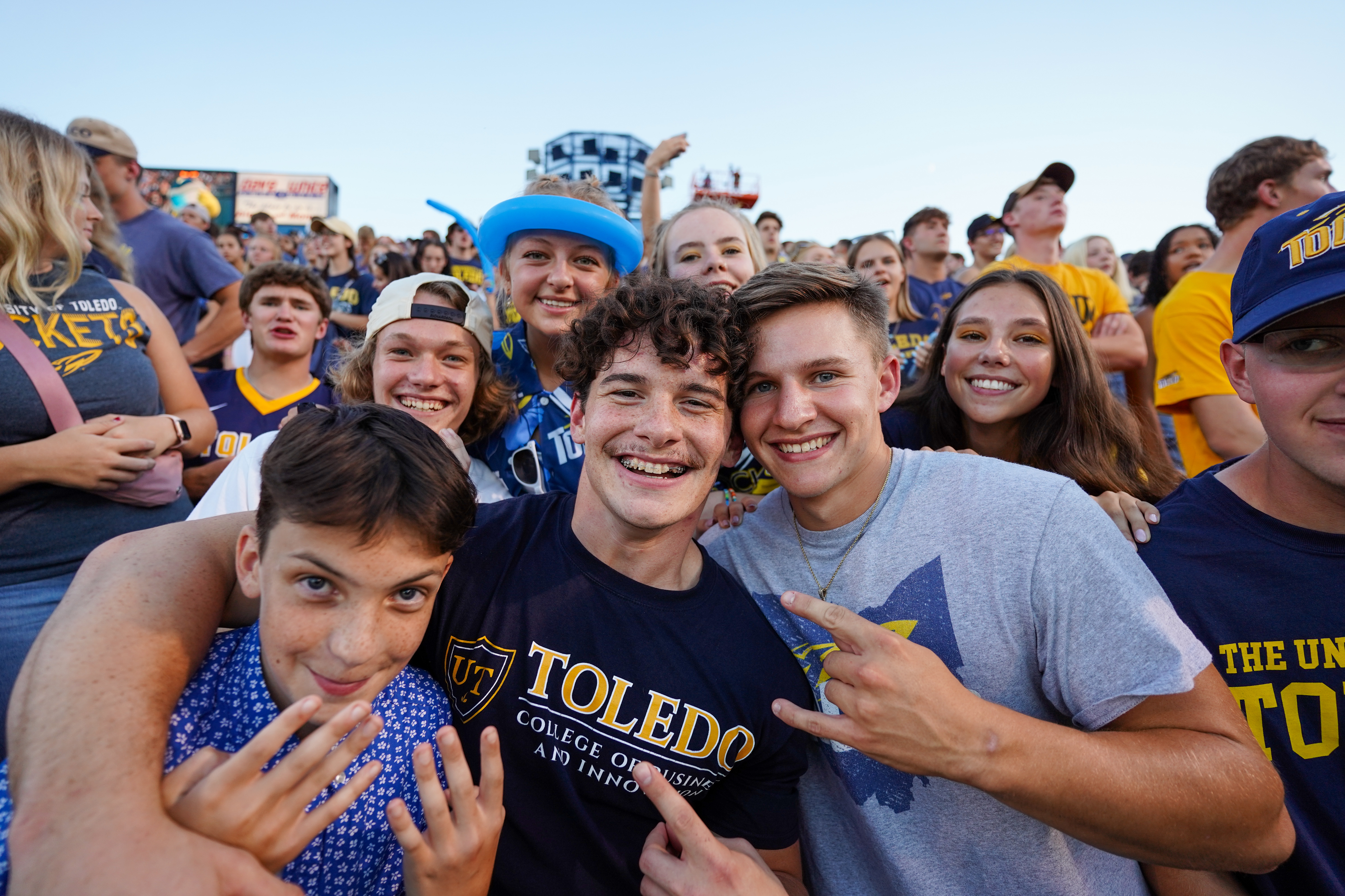 Three men smiling for the camera during a Toledo Rocket Football game.